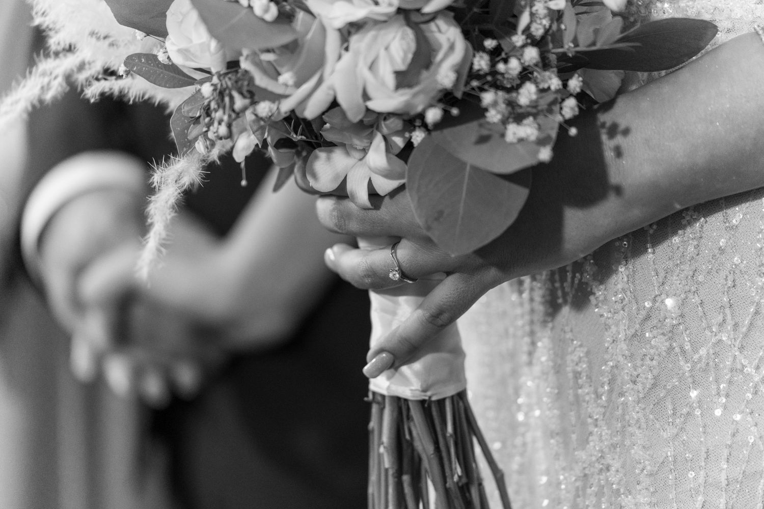 Black and white detail shot of hands holding a wedding bouquet with roses and delicate florals. νυφικό μπουκέτο.