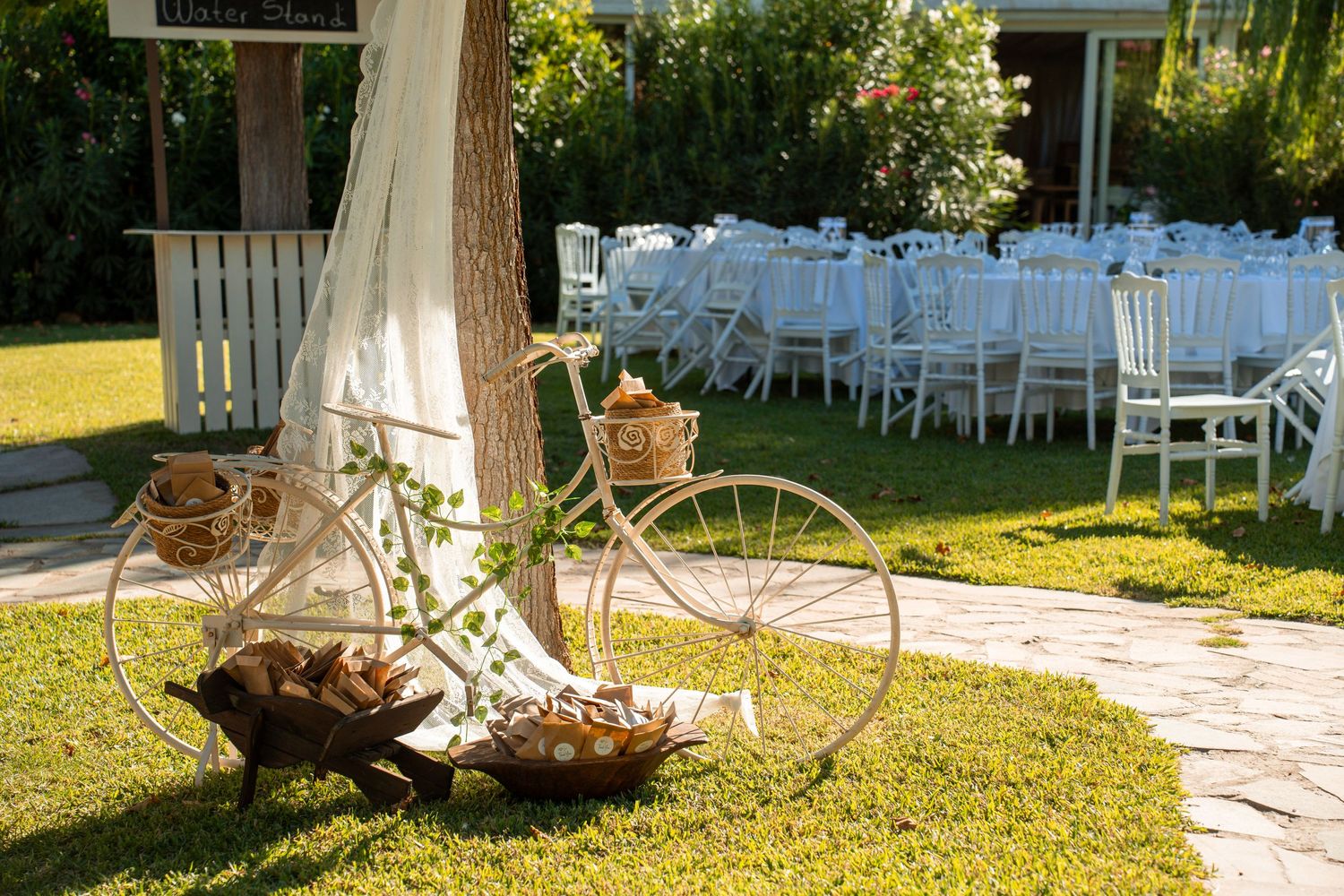 Vintage bicycle decoration with white chairs set up for outdoor wedding ceremony.