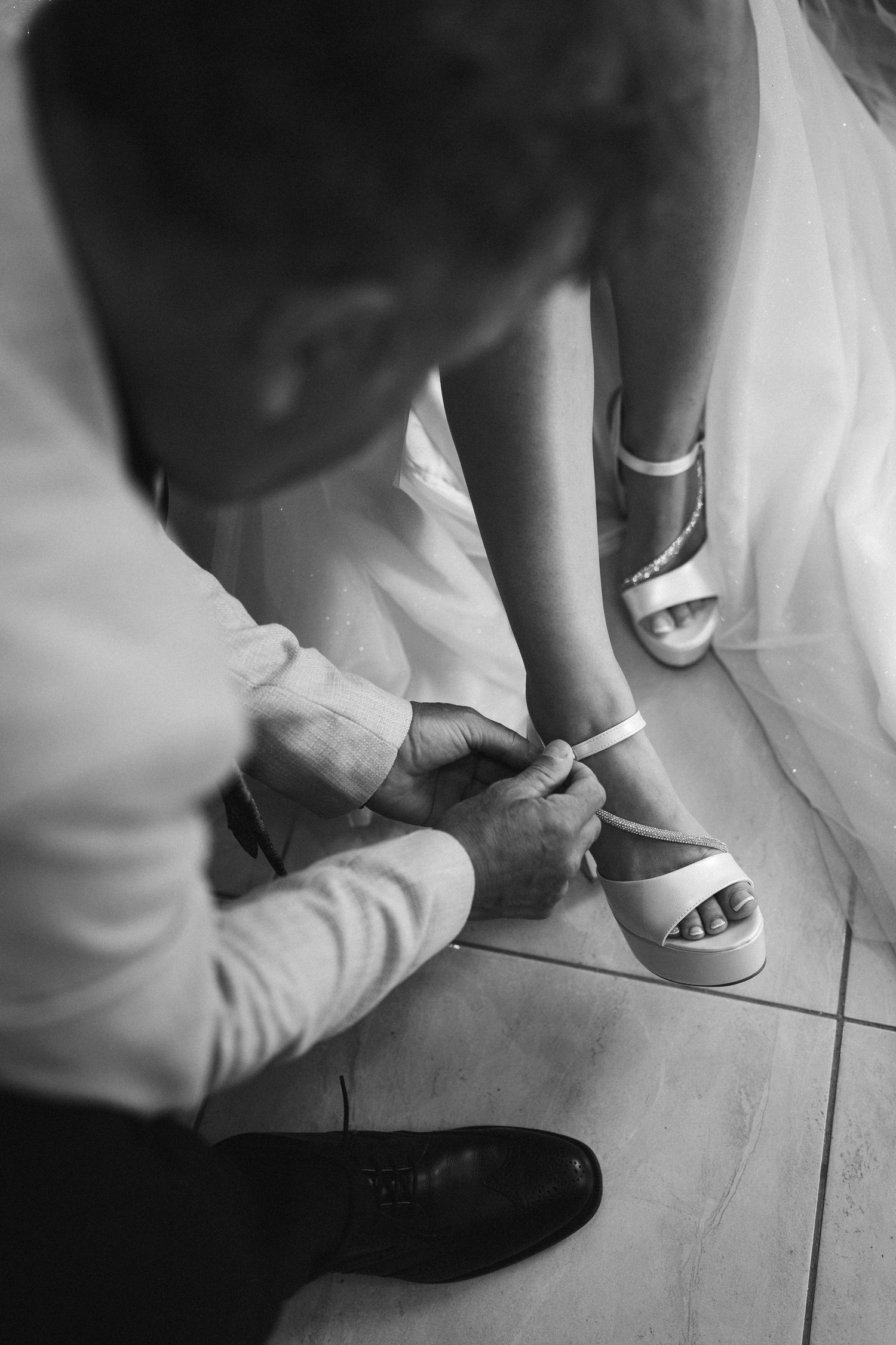 A series of black and white photos showing elegant bridal shoes and sandals on a tiled floor.