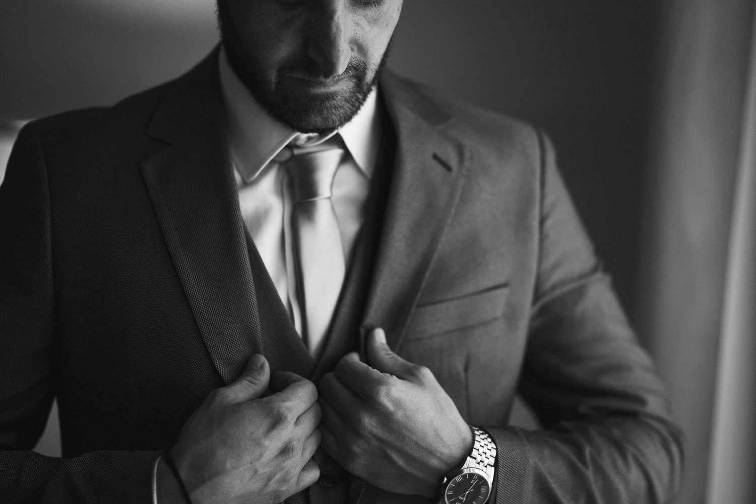 Close-up of formal attire details showing suit jackets and ties being adjusted.
