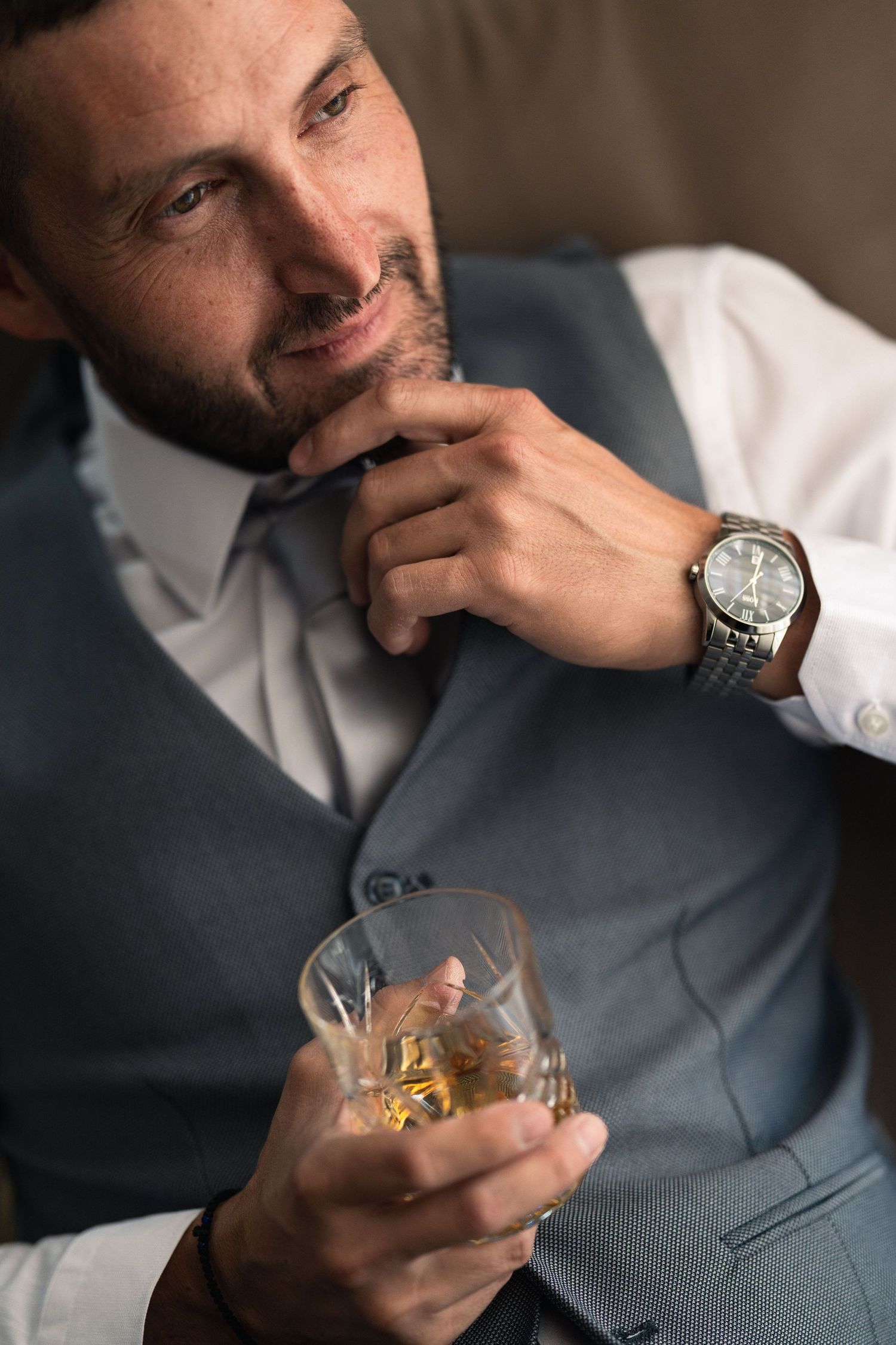 A sequence showing someone in a grey vest holding and examining a glass of whiskey.