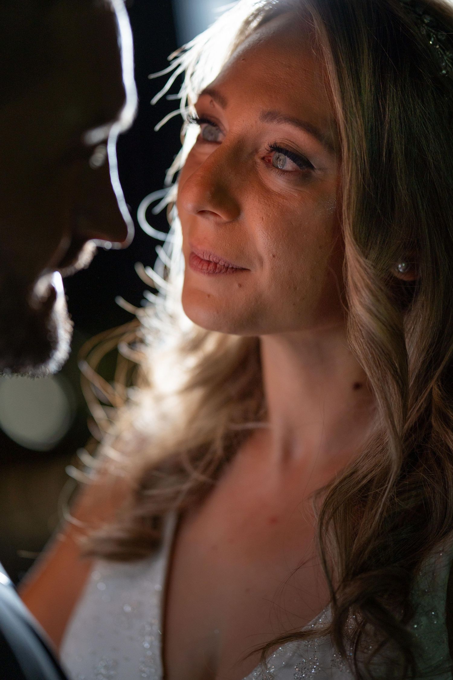 Artistic portrait with dramatic lighting capturing bridal makeup and hair details.