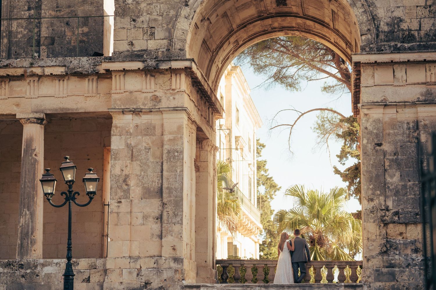 Stone archways and columns of a historic Mediterranean building captured in warm evening light.