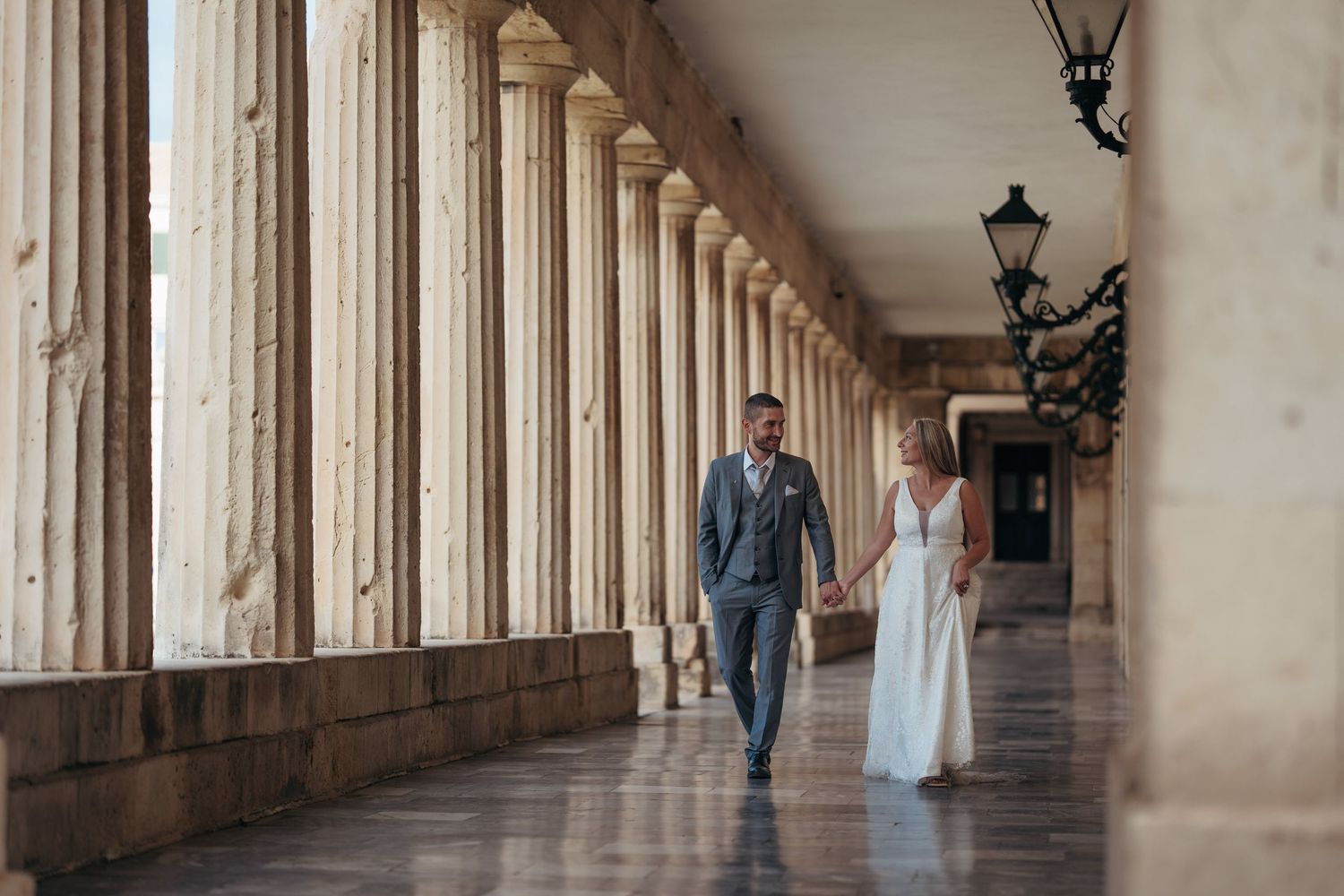 Elegant architectural colonnade with stone pillars creating a dramatic perspective for a wedding photo shoot.