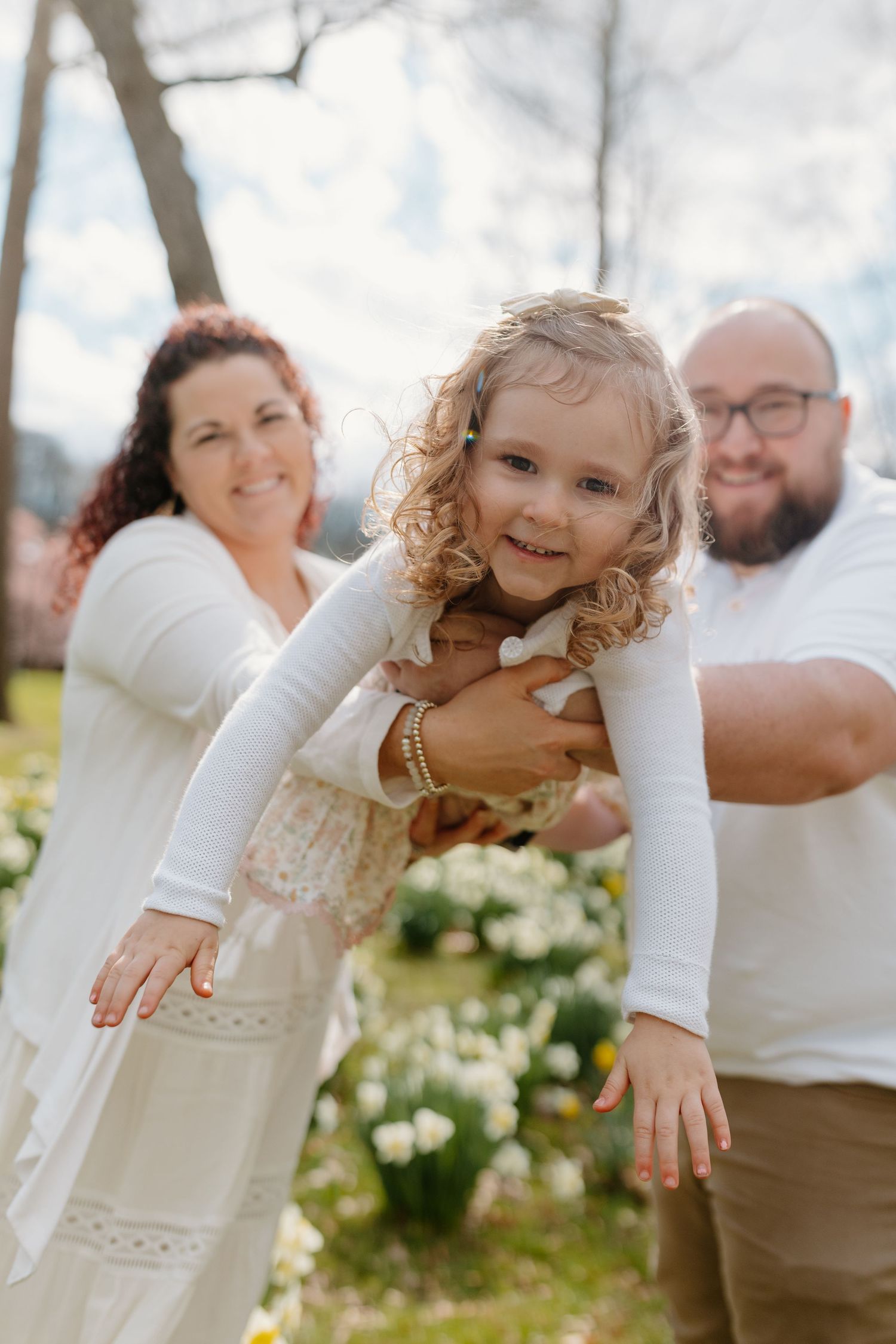 Playful family photo session outdoors with white and cream color coordination.