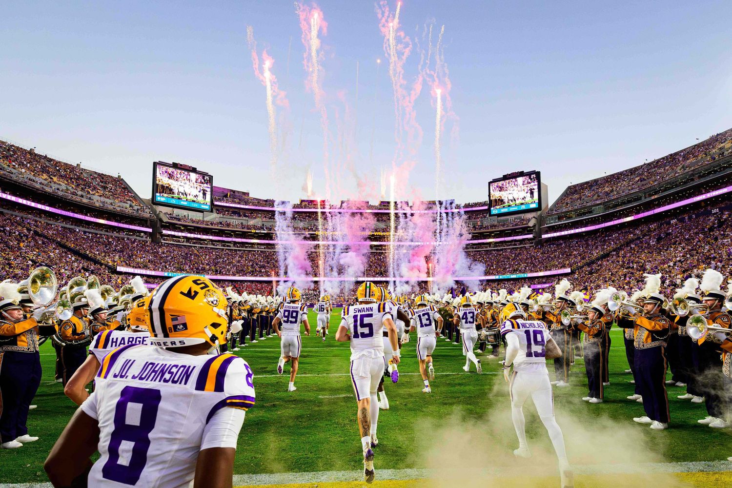 Stadium celebration with pink pyrotechnics during LSU football game.