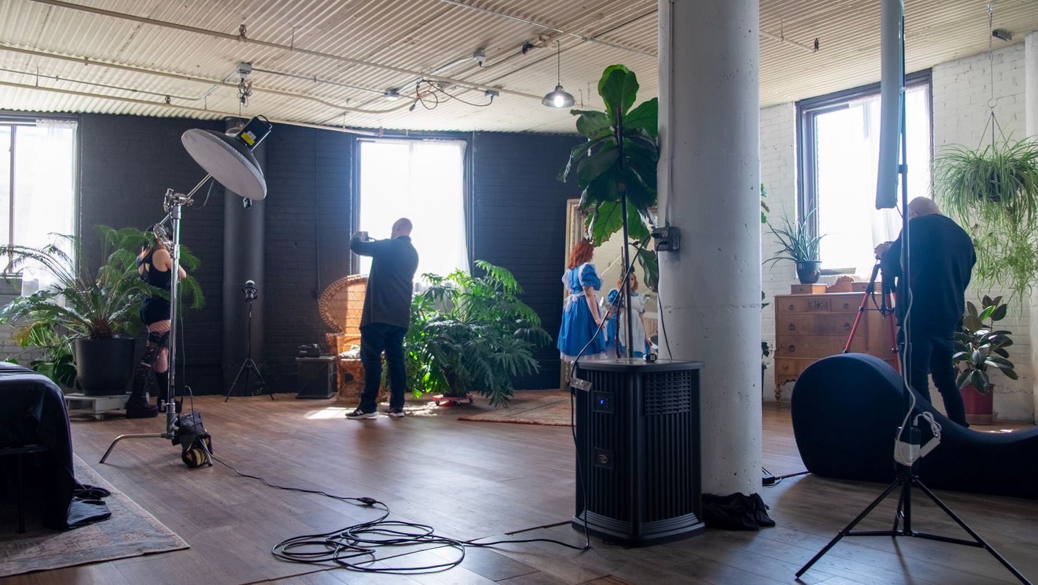 People setting up recording equipment in a modern office space with indoor plants and large windows.