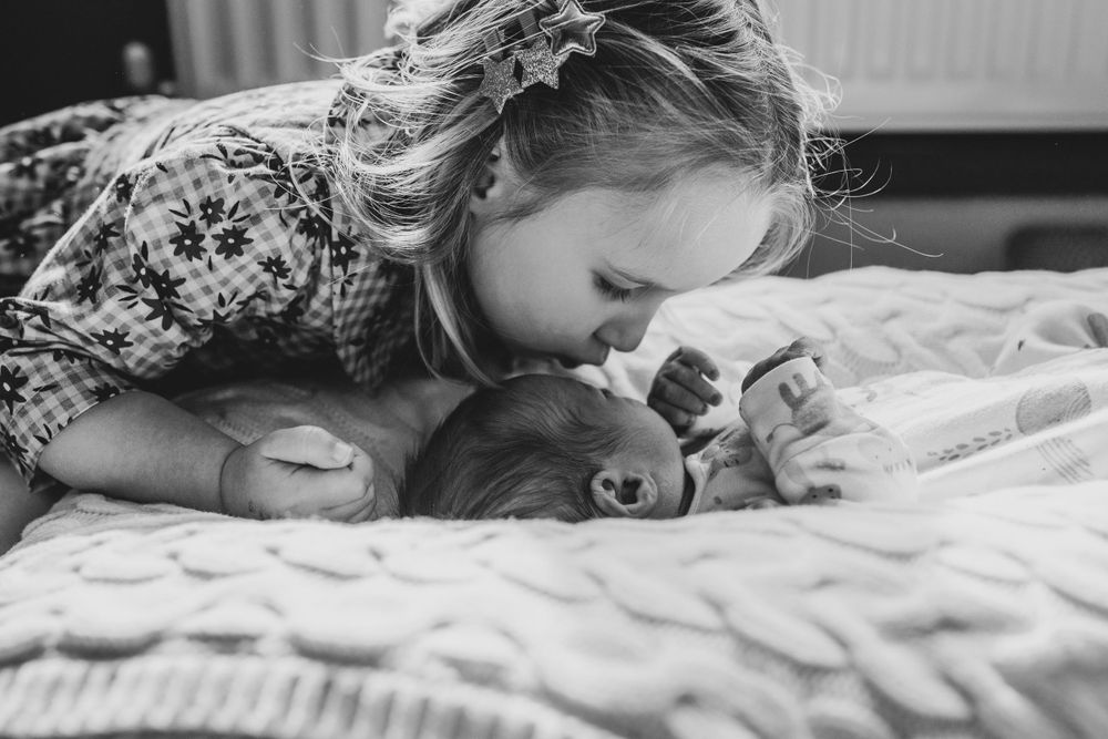 Tender black and white moment shared between parent and infant laying together on soft textured bedding.