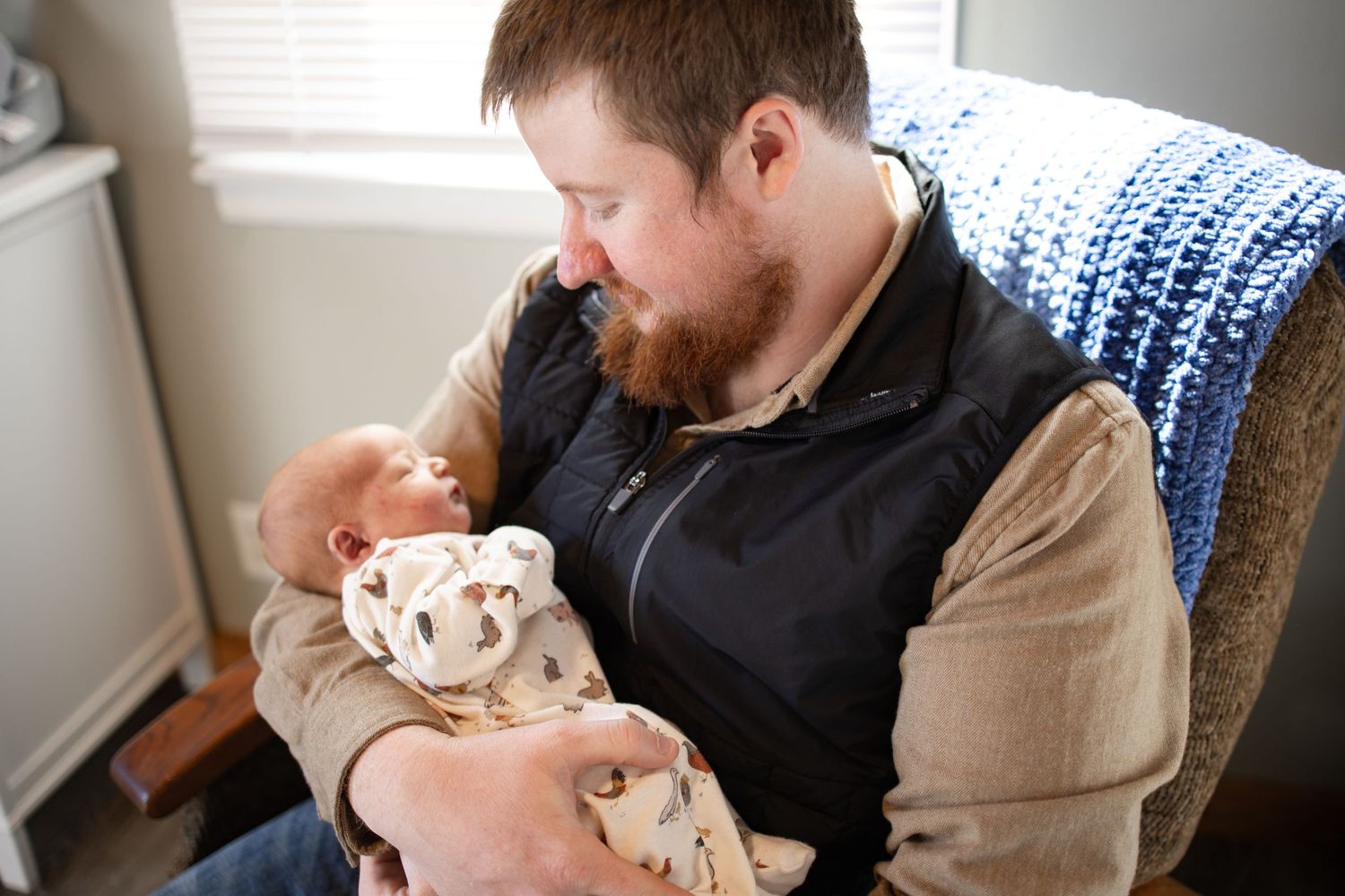 Springfield, IL Newborn Photographer captures a dad holding a smiling at his newborn during a lifestyle newborn session