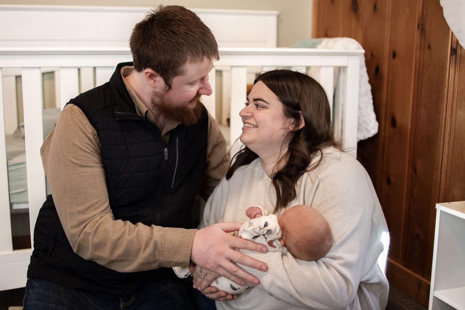 Springfield Il Newborn Photographer captures mom and dad looking at each other with their newborn during a lifestyle newborn session