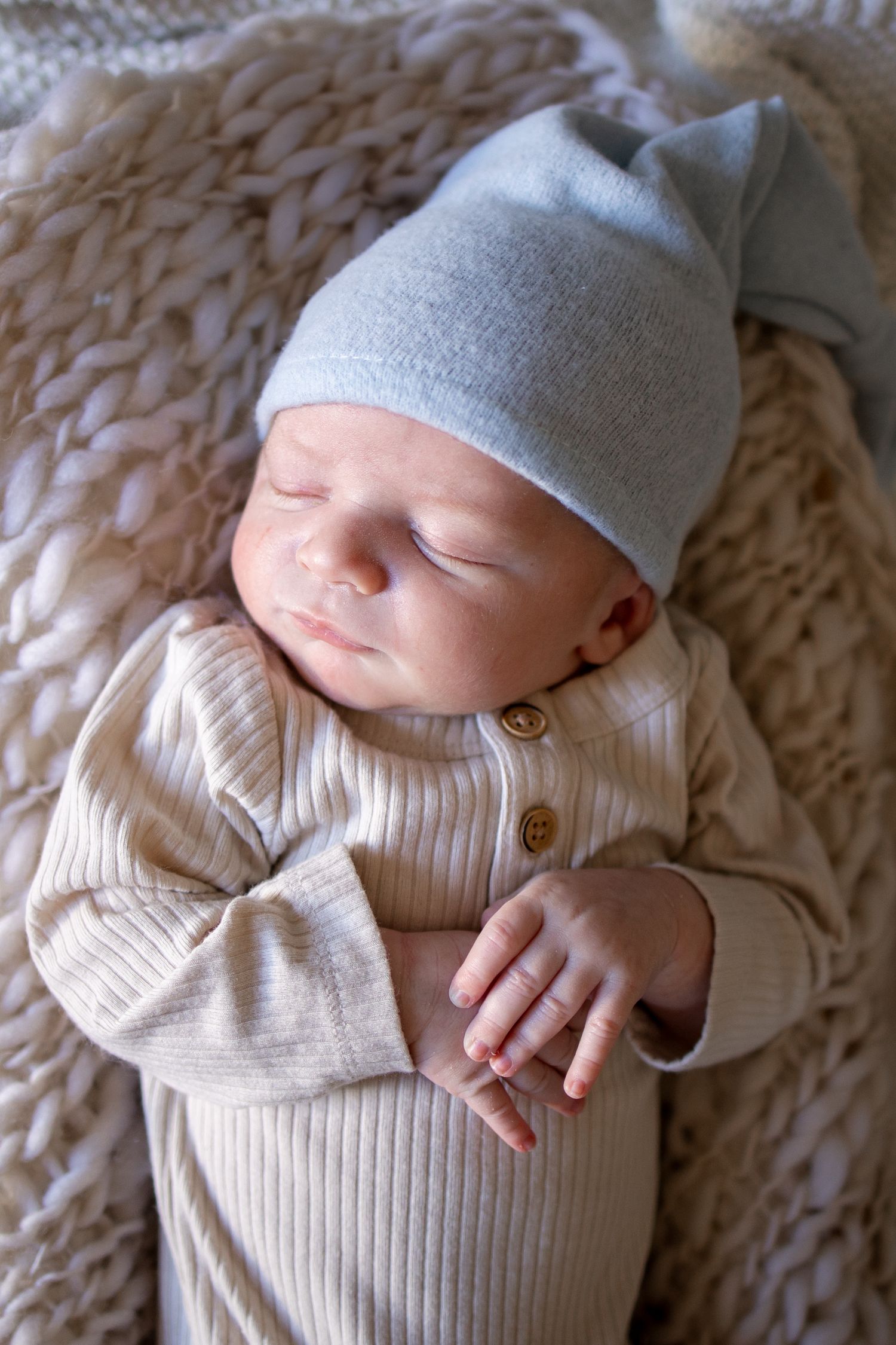 Springfield IL Newborn Photographer | Newborn folding hands while sleeping on blankets during a lifestyle newborn session