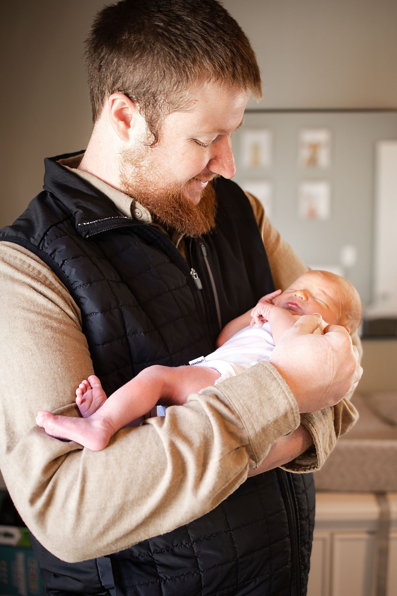 Springfield, IL Newborn Photographer captures a dad holding and looking at his newborn during a lifestyle newborn session in Central, IL