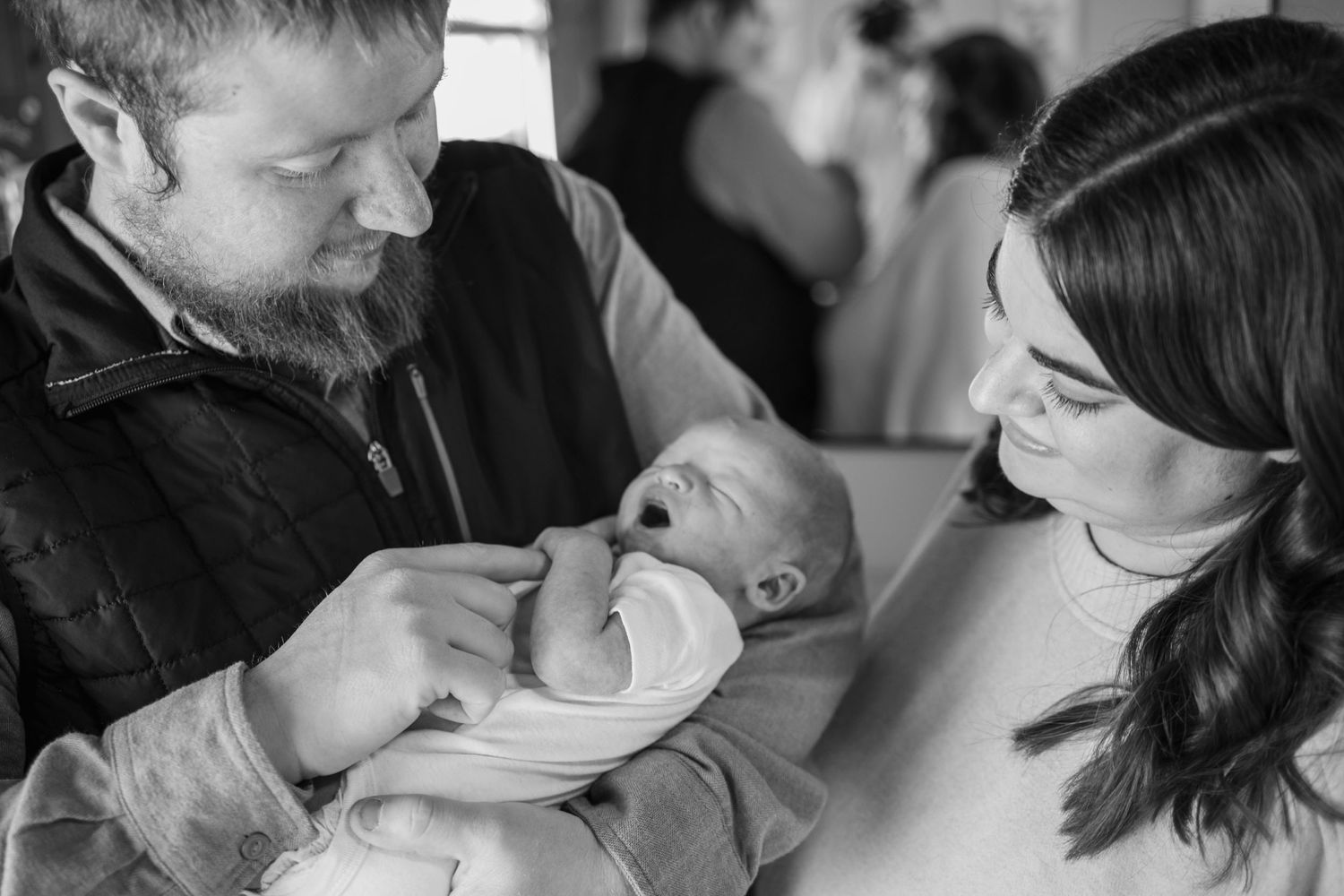 Springfield IL Newborn Photographer captures mom and dad holding baby between them and smiling at him during a lifestyle newborn session