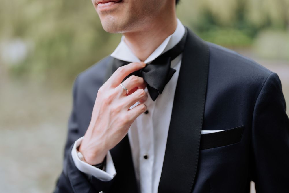 Close-up view of formal black tuxedo with bowtie and white pocket square detail.