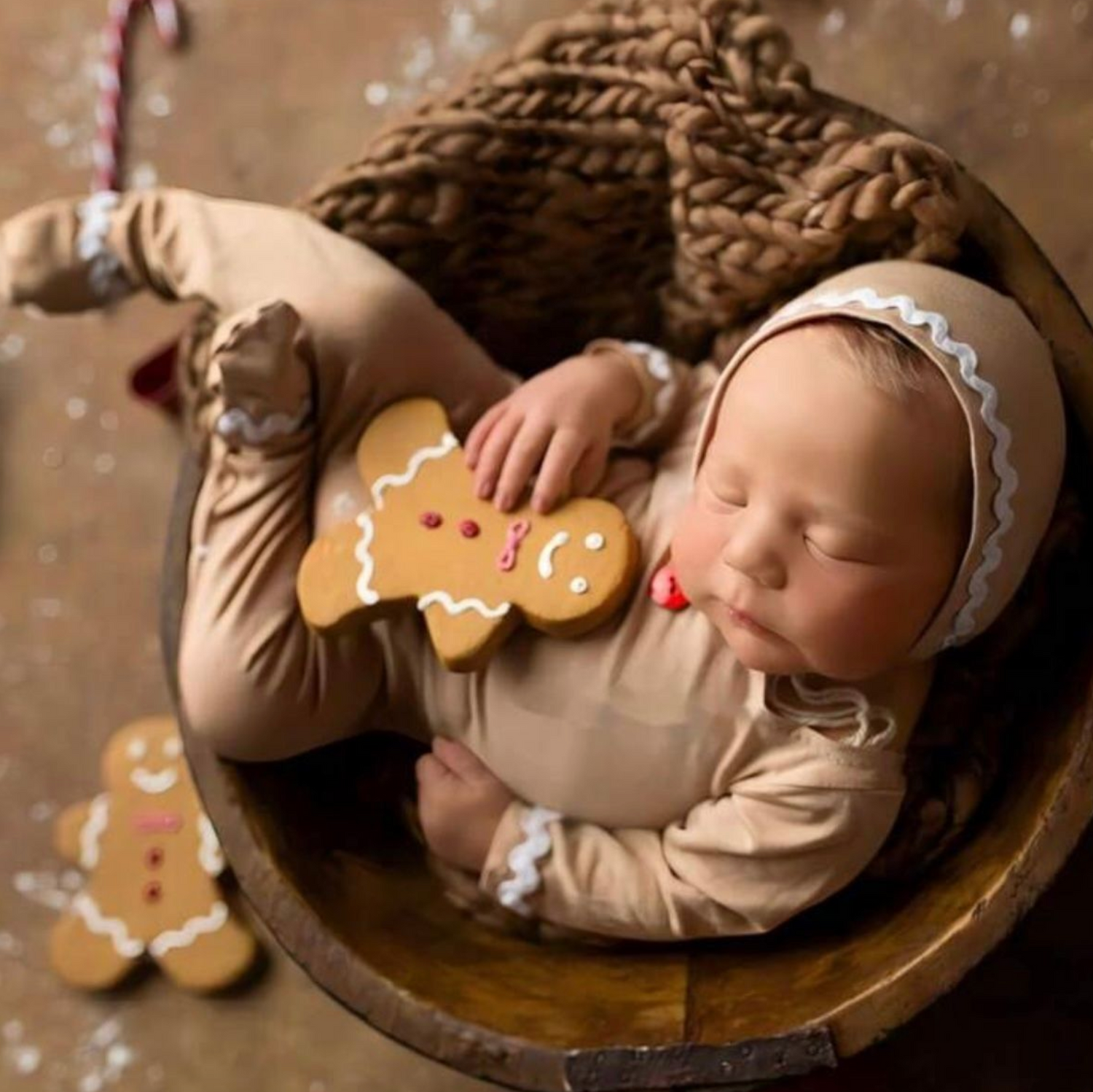 Overhead view of gingerbread cookies on a rustic brown plate with festive holiday decorations.