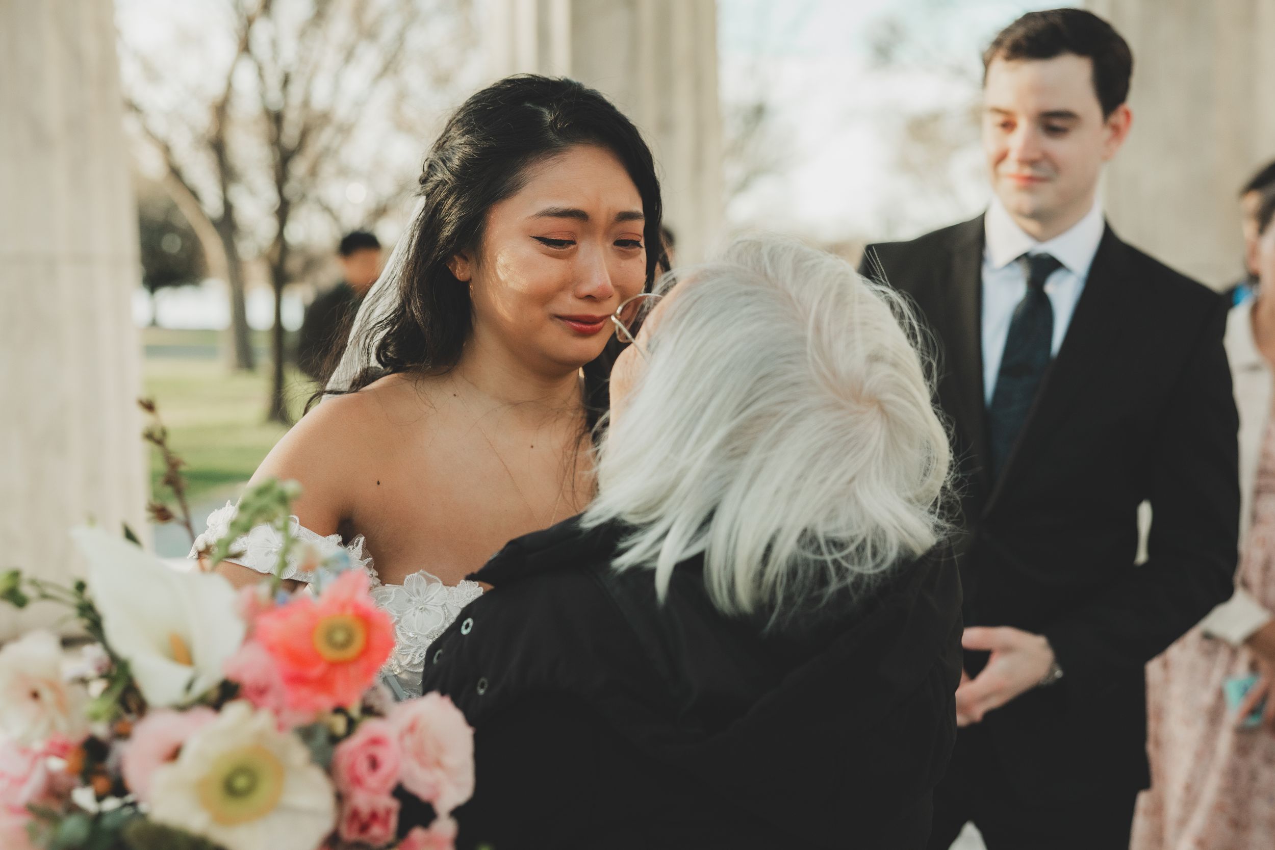Emotional bride wiping tears as an her grandmother congratulates her at her wedding.