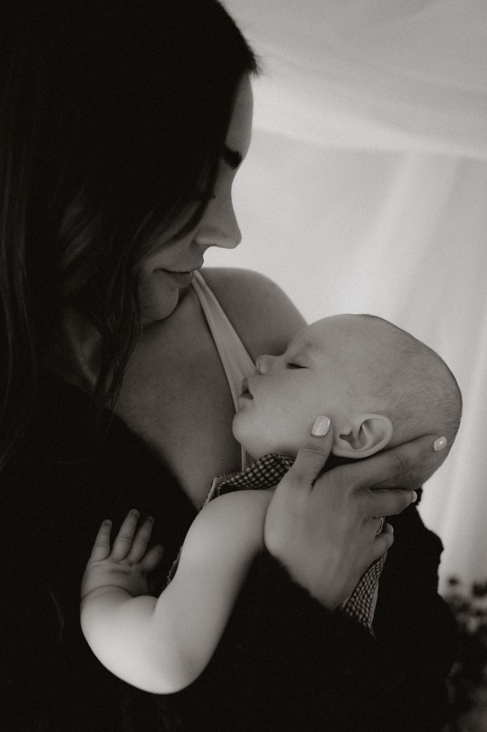 Black and white photo of a mother tenderly breastfeeding her newborn baby, cradling the infant in her arms.