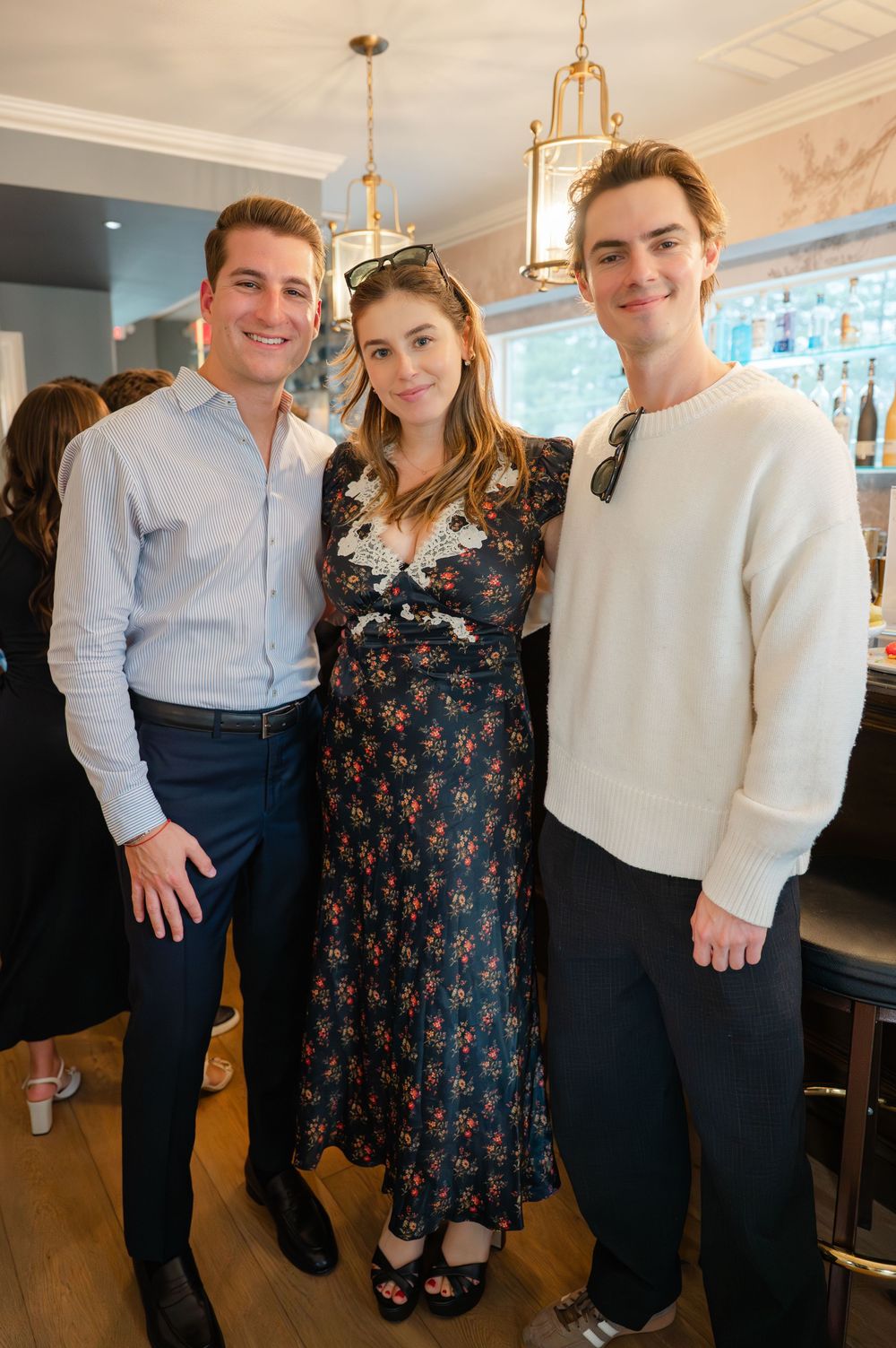 Three guests smiling together at elegant bridal shower event inside restaurant.