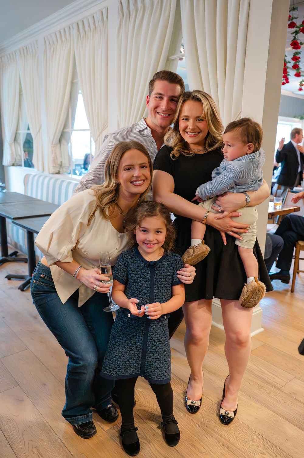 Happy family group posing with two children at a festive indoor celebration event.