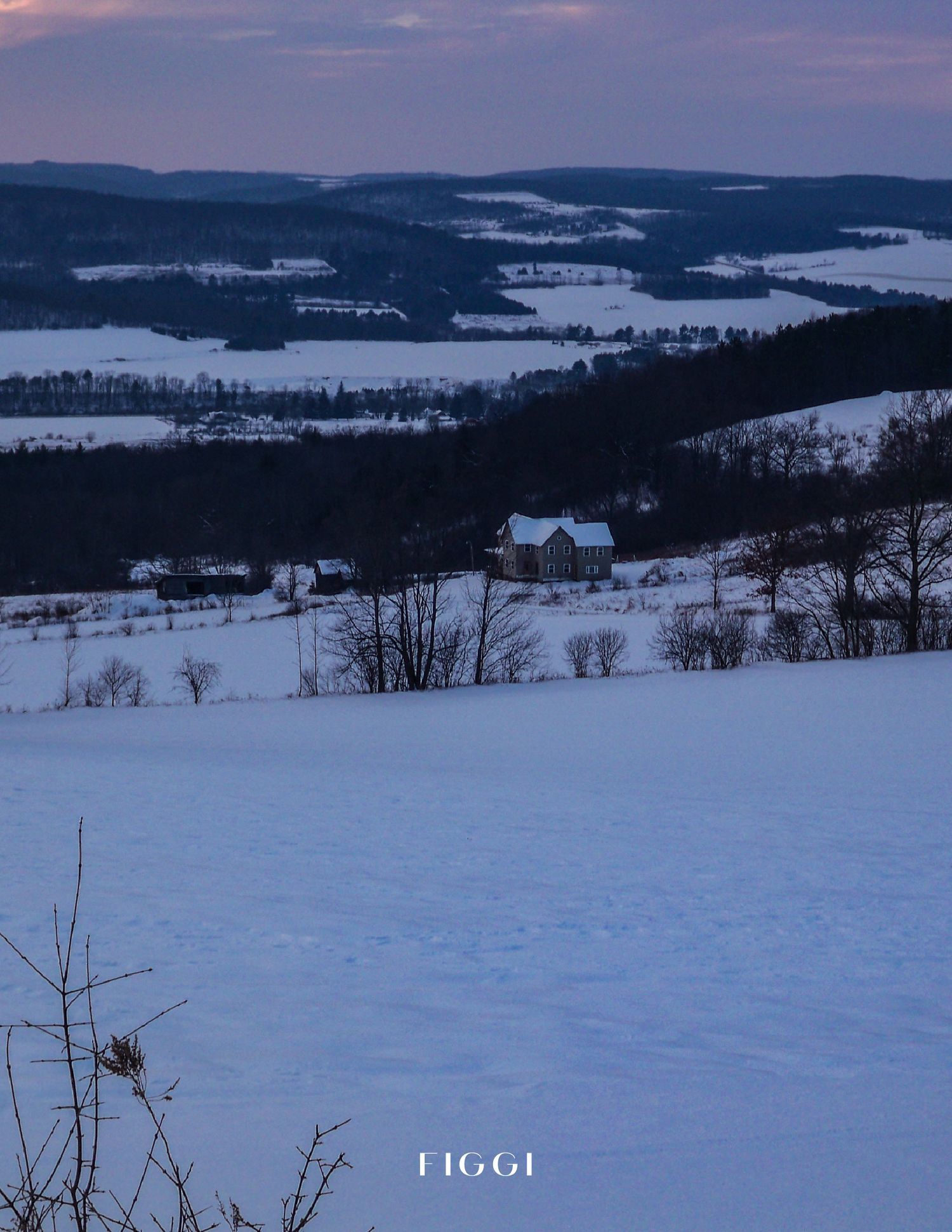 Snowy winter landscape at dusk with a farmhouse nestled in a valley surrounded by rolling hills and dark evergreen trees.