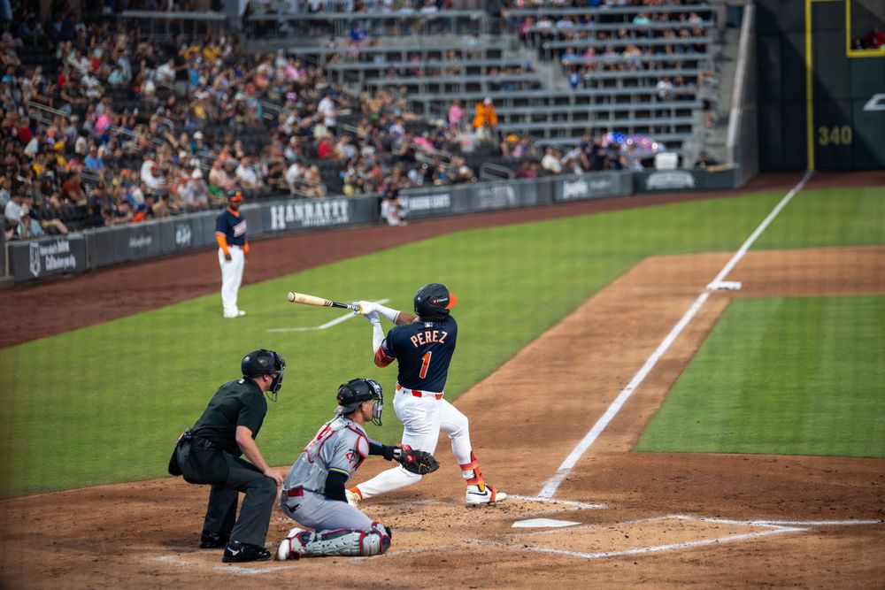 Baseball batter Perez makes contact with pitch as catcher and umpire watch at home plate.