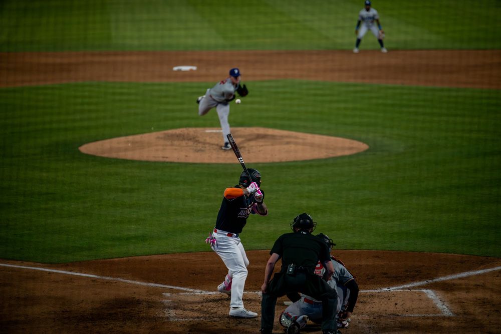 Wide angle view of baseball pitcher throwing to batter with catcher positioned at home plate.