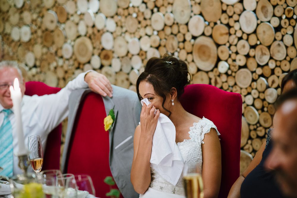 Bride and groom share a tender embrace among lush green lemon trees in an outdoor garden wedding setting.