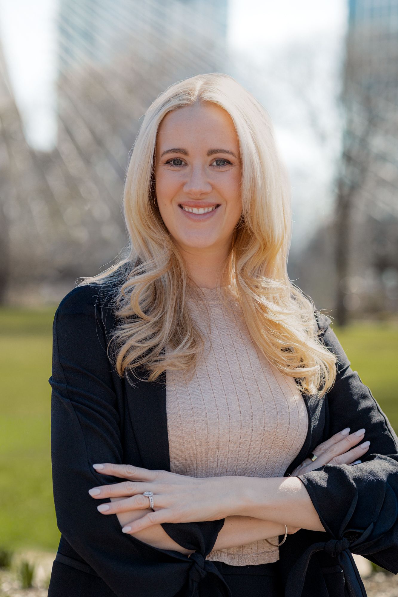 Smiling blonde woman in gray blazer holding yellow toy construction loader near stack of colorful books.