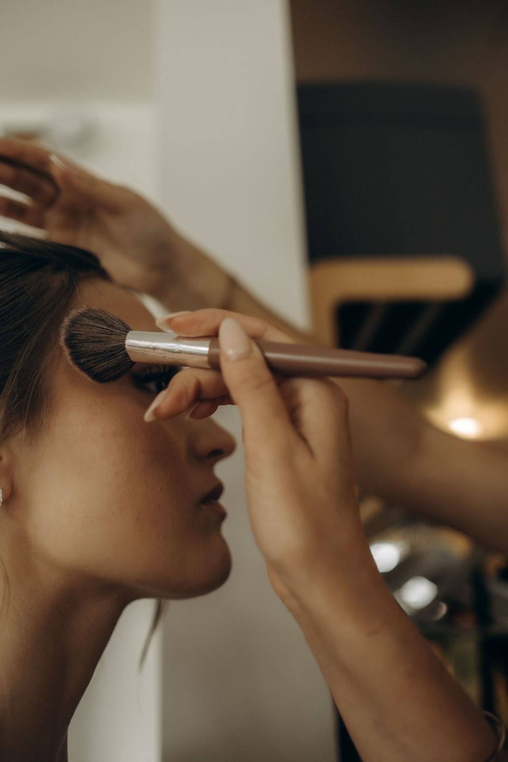 detail of bridesmaid's hand fixing bride's makeup being captured by storytelling wedding photographer in Stockholm