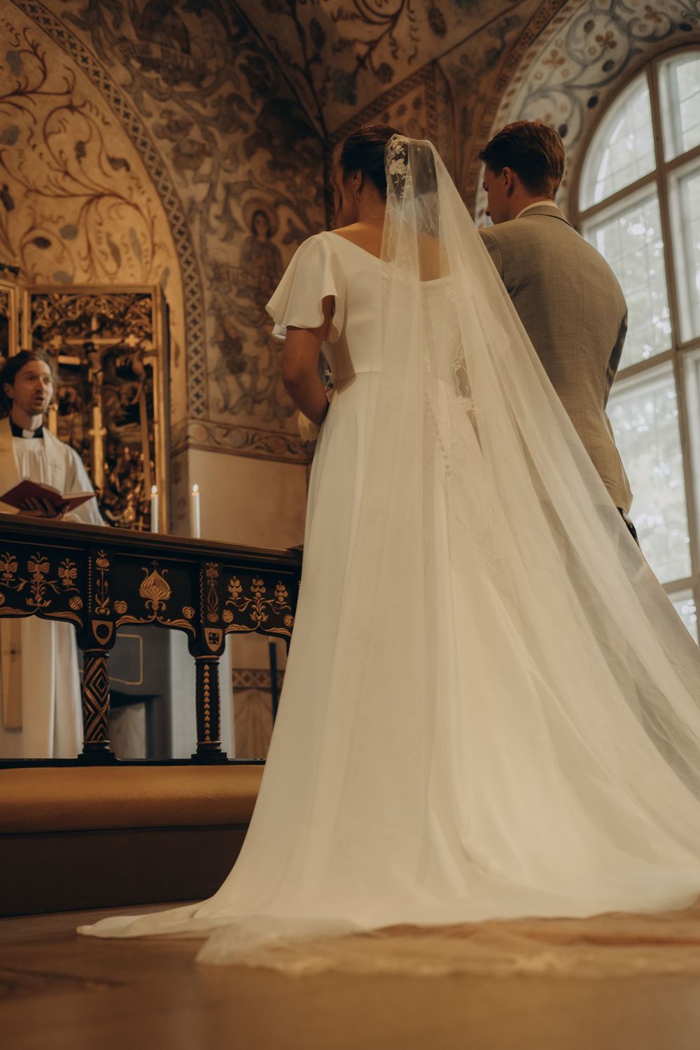 wedding couple standing at the altar in church while being captured by storytelling wedding photographer in Stockholm