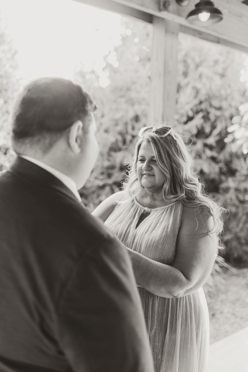 Black and white photo of a bride and groom sharing an emotional moment during outdoor wedding ceremony.