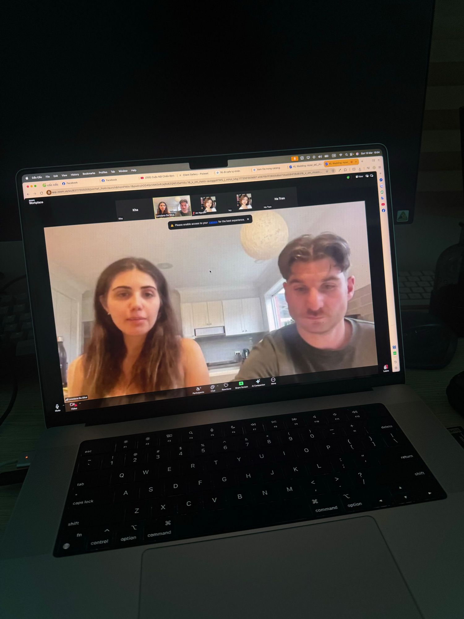 Couple on a video call displayed on a laptop screen in a dimly lit room.