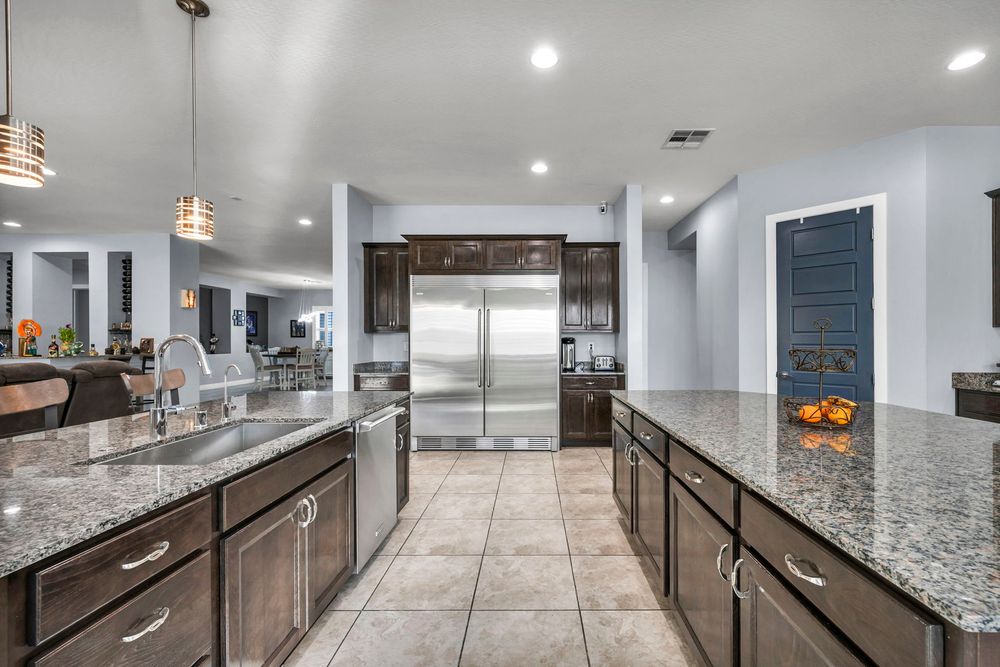 Spacious kitchen with dark wood cabinets, granite countertops, stainless steel appliances, and tile flooring.