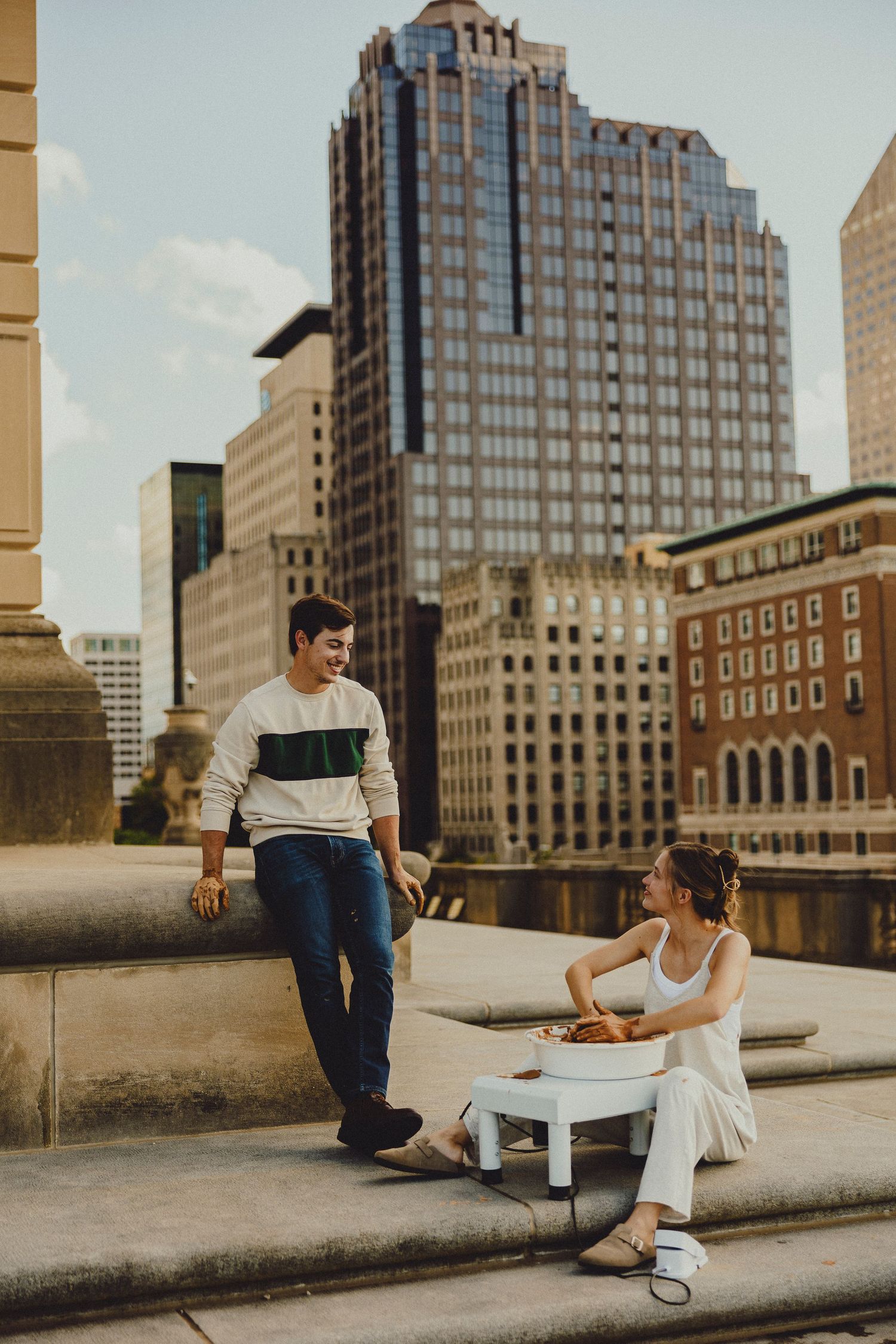 Couple enjoying a rooftop picnic with city skyline skyscrapers in the background on a sunny day.