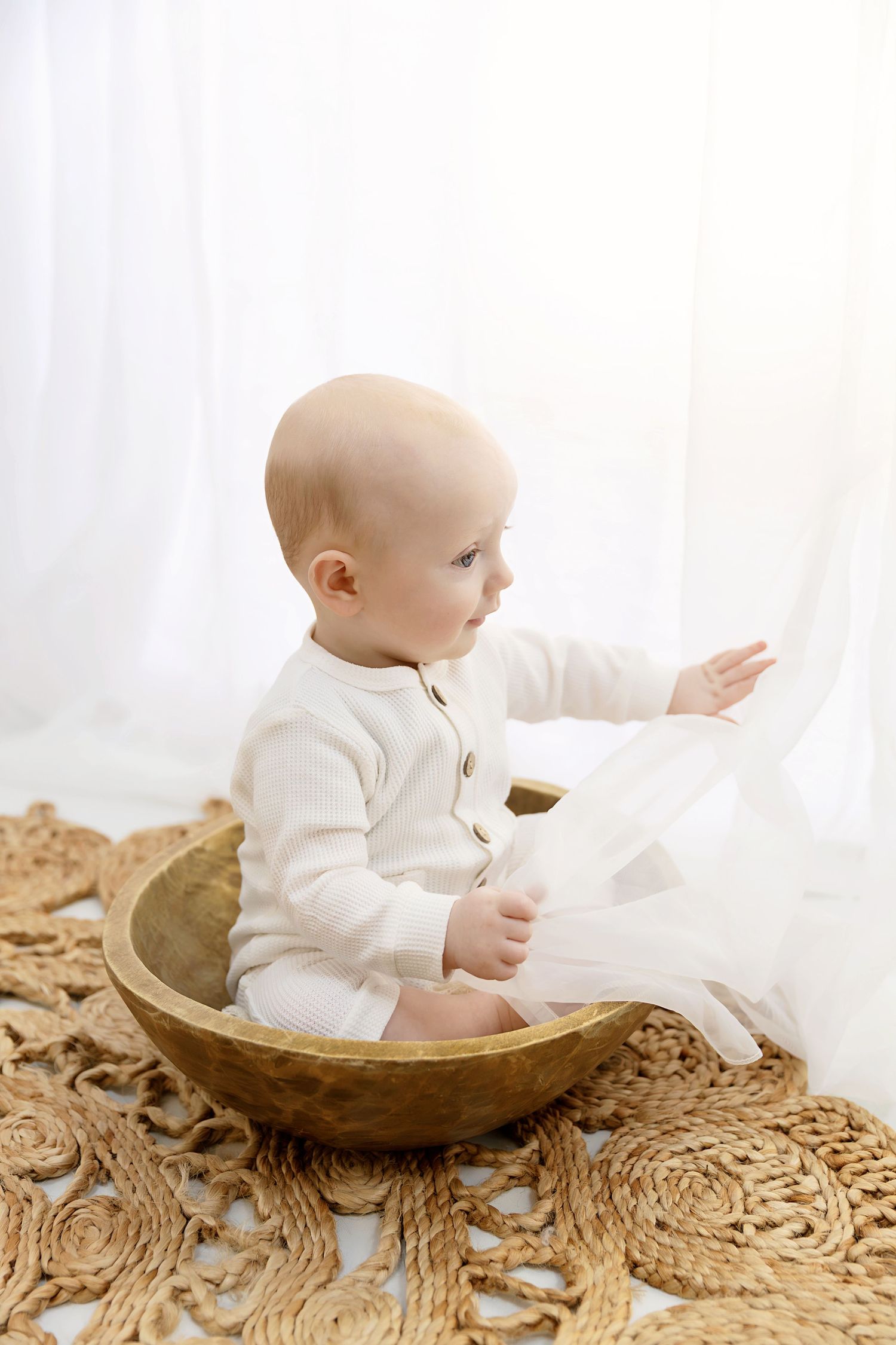 Little boy sitting in a bowl playing with curtains at his sitter session in Coventry with Shelly Loxton Photography