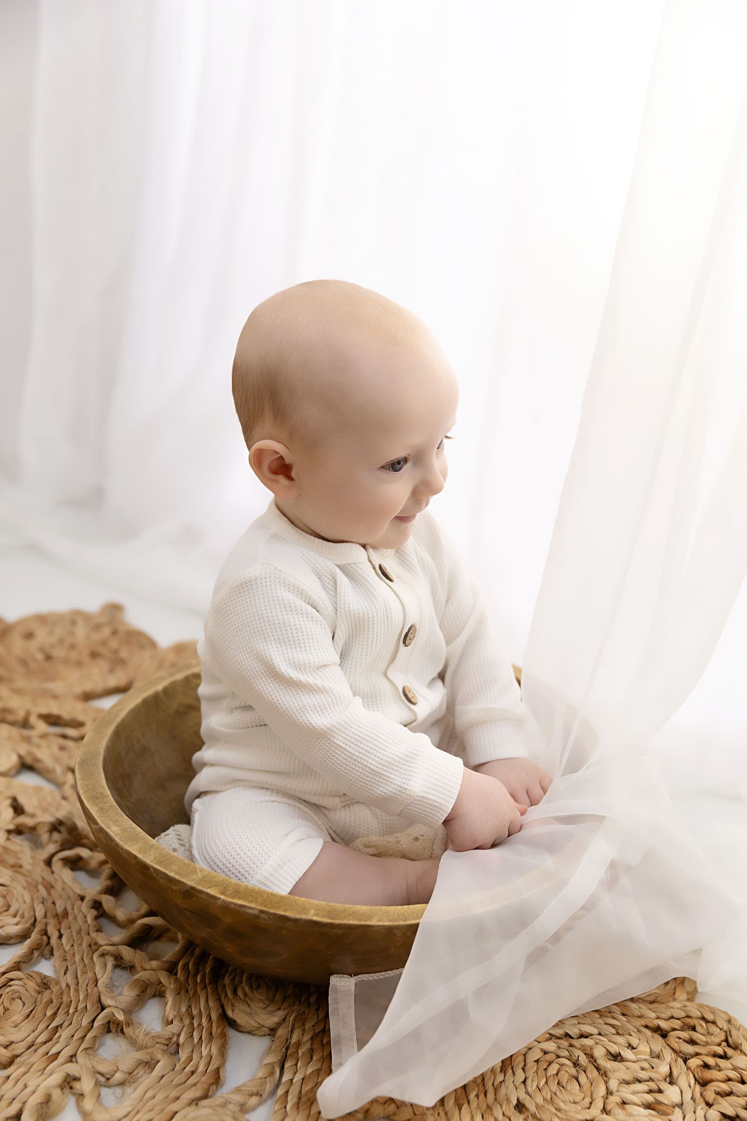Little boy sitting in a bowl playing with curtains at his sitter session in Coventry with Shelly Loxton Photography