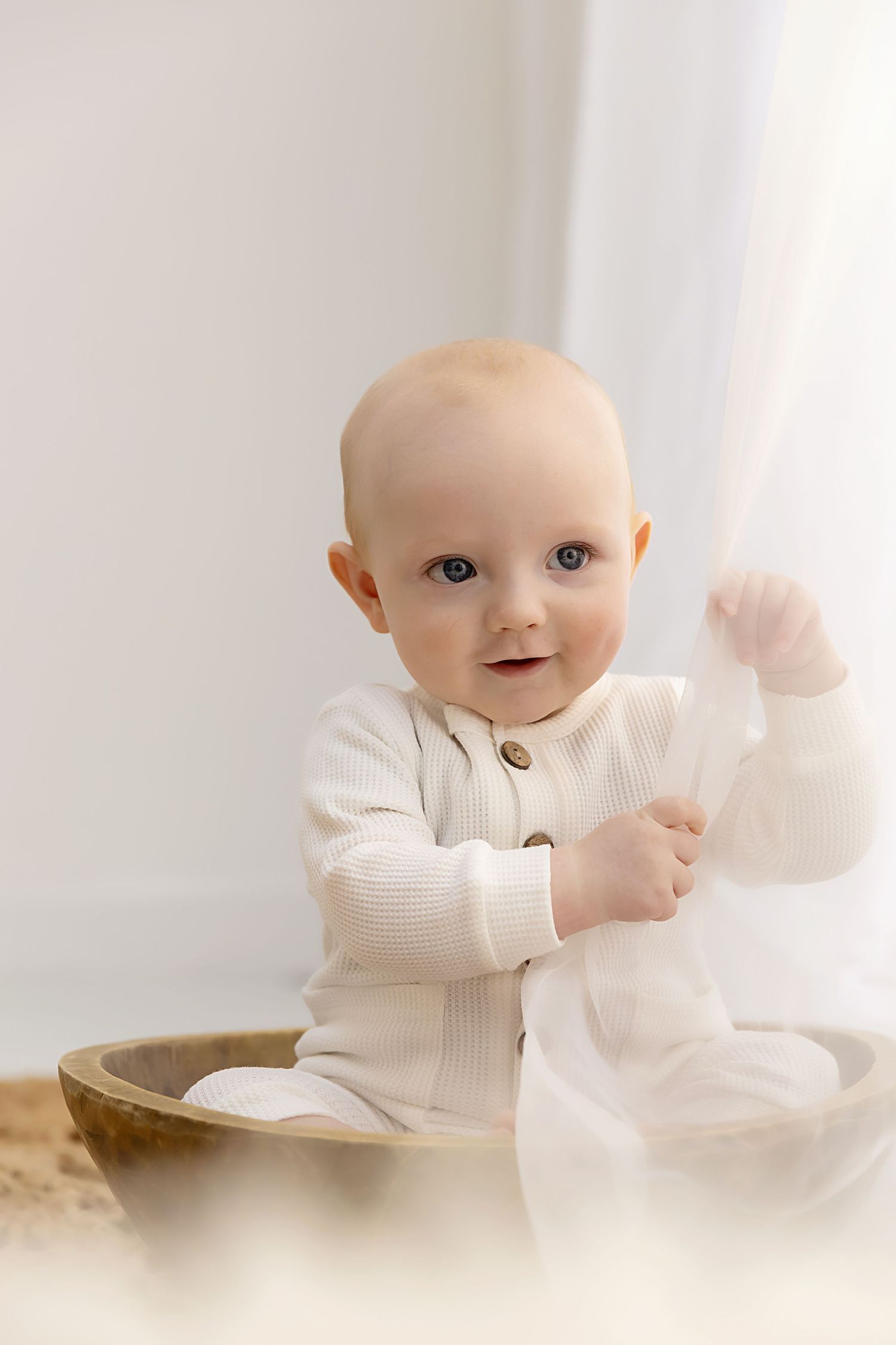 Little boy sitting in a bowl playing with curtains at his sitter session in Coventry with Shelly Loxton Photography