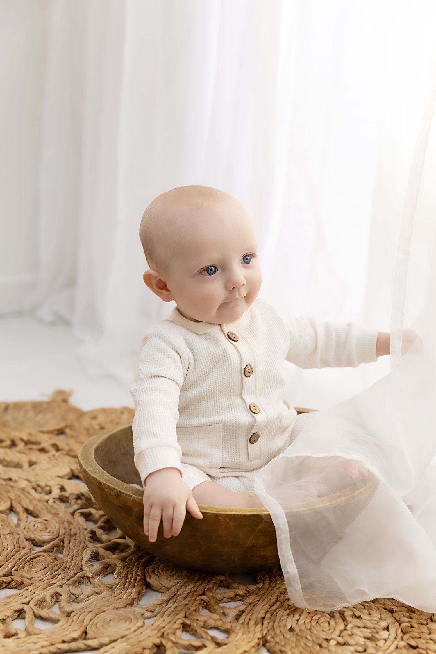 Little boy sitting in a bowl playing with curtains at his sitter session in Coventry with Shelly Loxton Photography