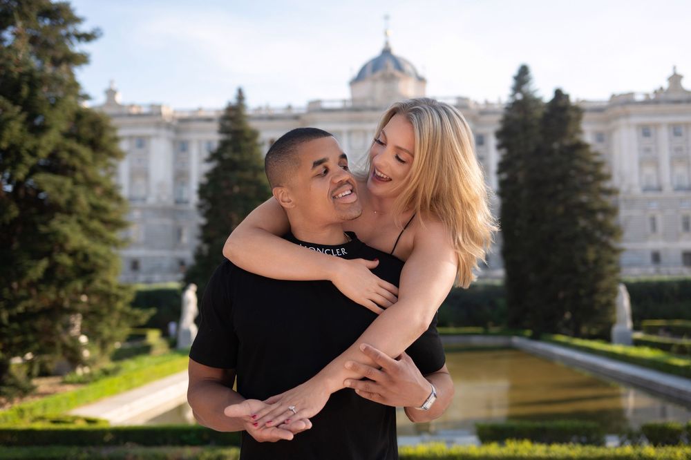 Happy interracial couple embracing and laughing in the gardens of the Royal Palace of Madrid.