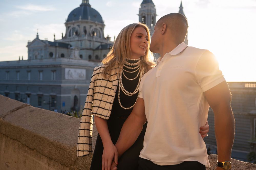 Couple sharing a romantic moment at sunset with a grand cathedral in the background in Madrid, Spain.