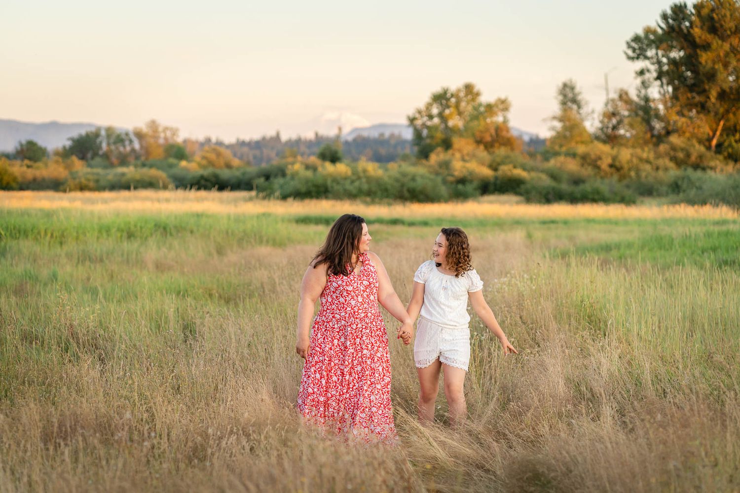 Mom and daughter walk in a grassy field at Marymoor Park.