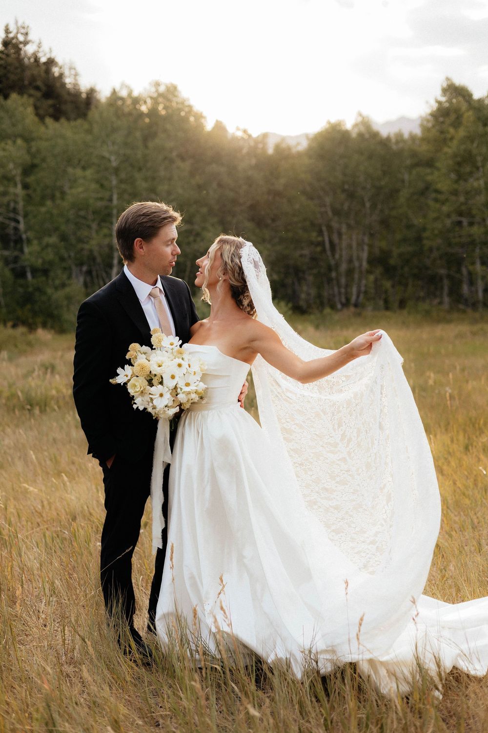 Bride and groom sharing romantic moment in golden field at sunset.