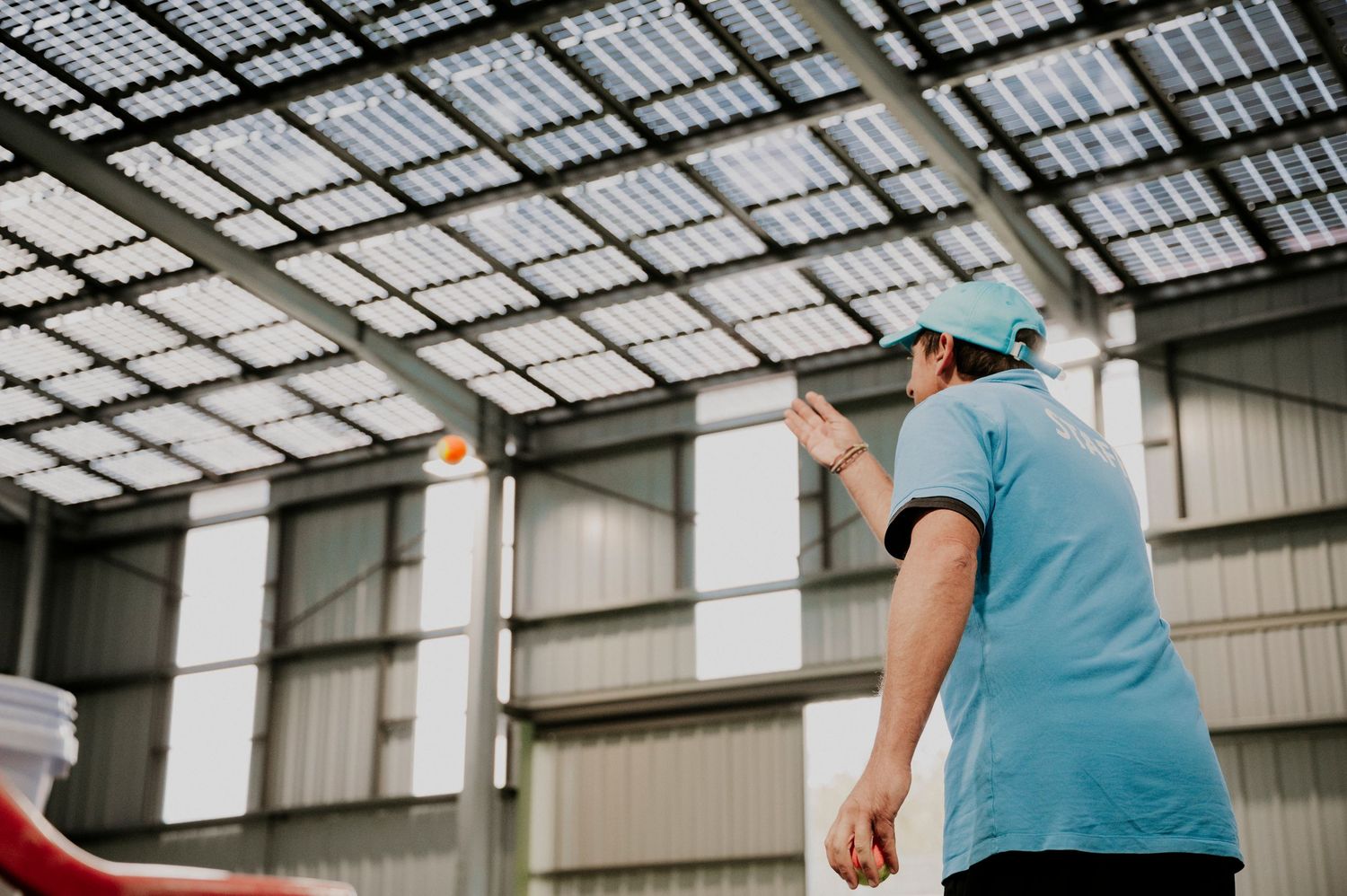 Prof de tennis photographié de sous une ombrière photovoltaïque par Thibaut Deligey, Autan Blanc.
