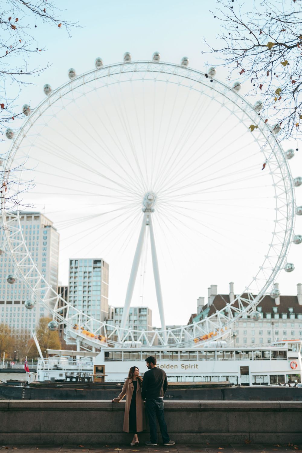 Couple standing together in front of the iconic London Eye ferris wheel on the South Bank.