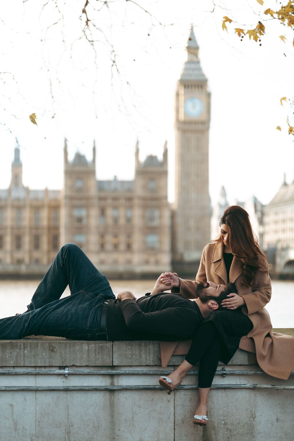Romantic couple relaxing on a wall with Big Ben and the Houses of Parliament in the background.