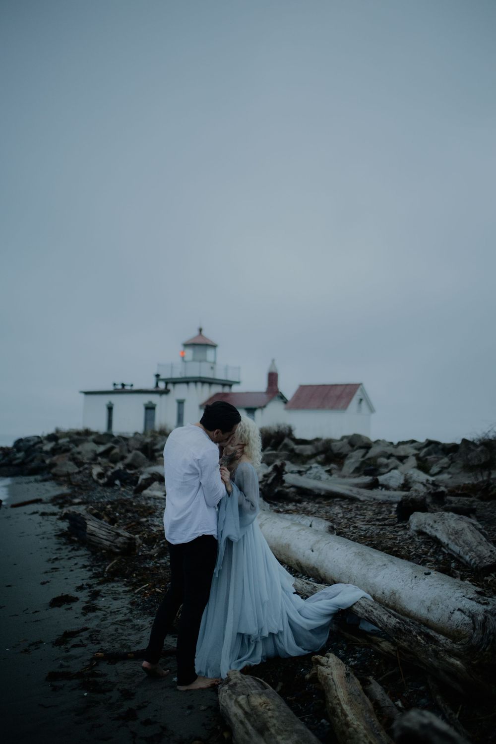 A dreamy coastal scene with two people by a lighthouse on rugged rocky shores.
