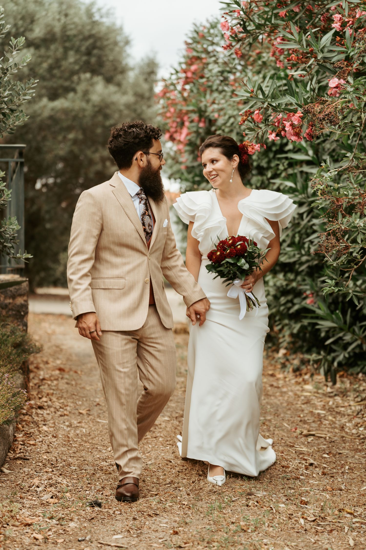 Fotografia de casamento captando a felicidade dos noivos, que sorriem juntos ao lado de um bolo decorado, num cenário ao ar livre.