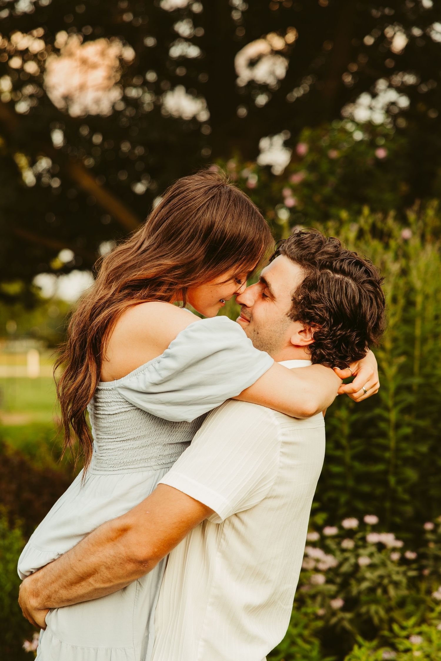 A romantic outdoor embrace between a couple in a garden setting with soft golden lighting.