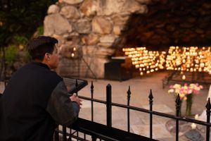Graduate praying at the Grotto at dusk.