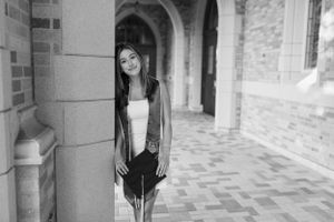 Black and white portrait of graduate posing in archway on campus.